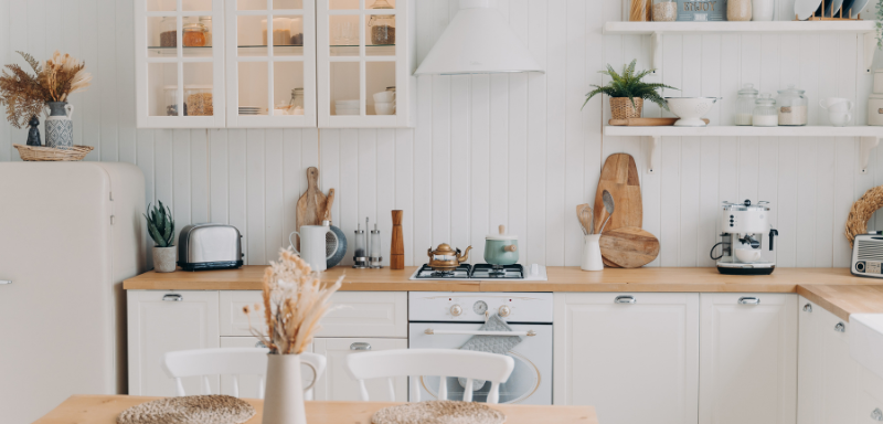 Modern rustic white kitchen with wooden countertops, open shelves, vintage fridge, coffee machine, and cozy dining area.